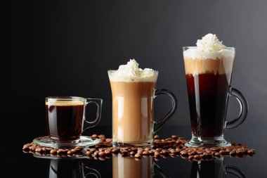 Siyah yansıtıcı arka planda çeşitli kahve içecekler.