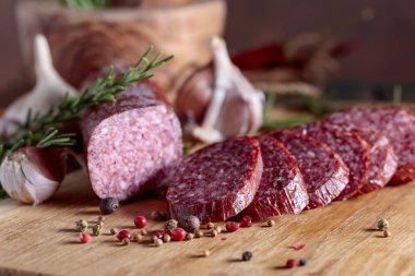 Eski ahşap bir masada tütsülenmiş salam. Biberiye, sarımsak ve biberli sosis..