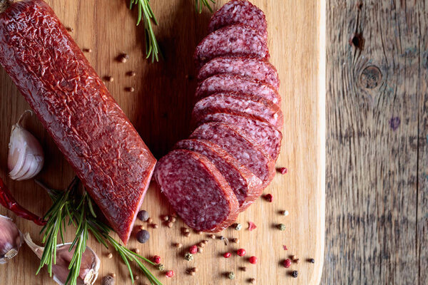 Smoked salami on a old wooden table. Sausages with rosemary , garlic and pepper. Top view.