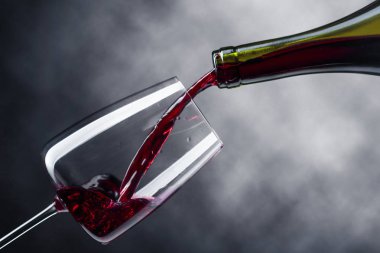 Kırmızı şarap şarap cam içine siyah bir arka plan üzerine dökülür varlık.