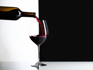 Kırmızı şarap bir bardak dökülür. Yansımalı arka plan, metniniz için kopya alanı.