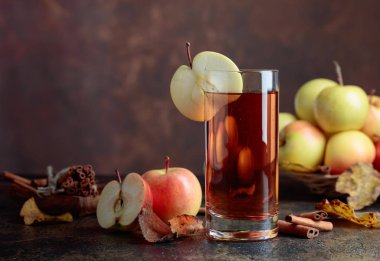 Bardak elma suyu veya elma suyu ile sulu elma ve tarçın bir mutfak masasında.