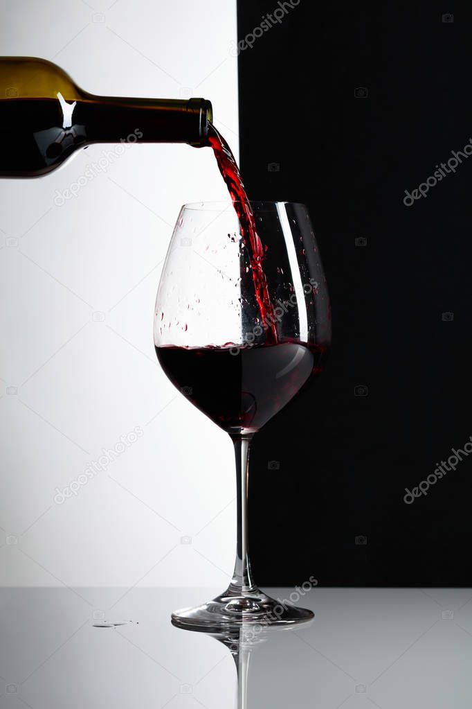 Red wine is poured into a glass. Reflexive background, copy space for your text.