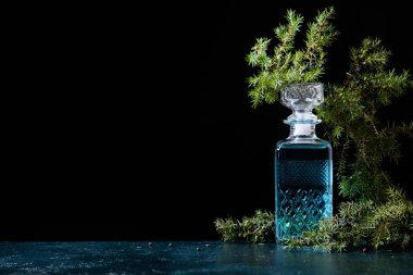 Mavi cin crystal sürahi ve ardıç daldaki meyveleri siyah bir arka plan ile. Metniniz için kopya alanı.