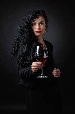 Siyah uzun kıvırcık saçlı Genç güzel kadın. Portre çekici esmer siyah bacground üzerinde kırmızı şarap ile.