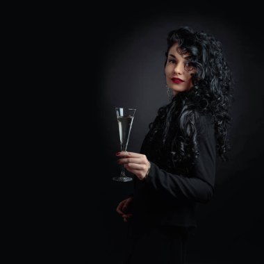 Siyah uzun kıvırcık saçlı Genç güzel kadın. Mutlu çekici esmer siyah bacground üzerinde beyaz şarap ile portresi. Kopya alanı.