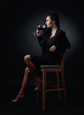 Siyah uzun kıvırcık saçlı Genç güzel kadın. Portre çekici esmer siyah bacground üzerinde kırmızı şarap ile.