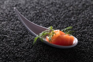 Siyah susam arka plan üzerine dereotu ile tuzlanmış somon dilim.