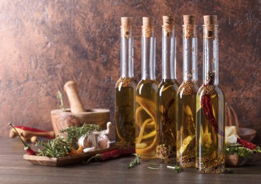 Şişe zeytinyağı eski ahşap bir masa üzerinde. Farklı baharatlar ve otlar ile zeytinyağı. Kopya alanı.