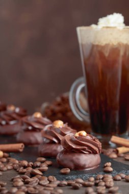  Fındık ve ahşap bir masa üzerinde kremalı kahve çikolata tatlı. Kahve çekirdekleri ve tarçın masanın üzerine dağılmış.