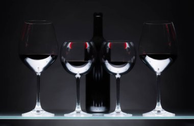 Gözlük ve karanlık bir arka plan üzerinde kırmızı şarap şişe.