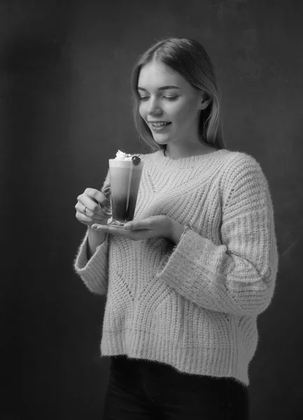 Attractive young woman with Irish coffee. Beautiful blonde in a sweater holding a mug of coffee with cream.