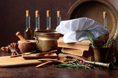 Beyaz şefin şapka ve eski yemek kitapları. Baharat ve mutfak masasında biberiye ile mutfak eşyaları.