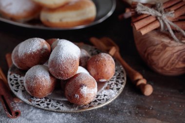Tatlı çörek, tarçın ve eski ahşap bir masa üzerine pudra şekeri.