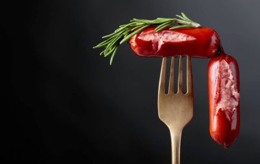 Izgara sosis ve çatalla biberiye. Siyah arkaplan, boşluğu kopyala. 