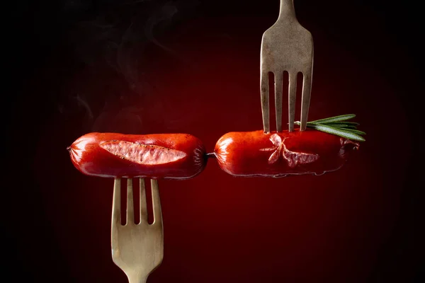 叉子上有迷迭香的烤香肠 深红色背景 复制空间 — 图库照片