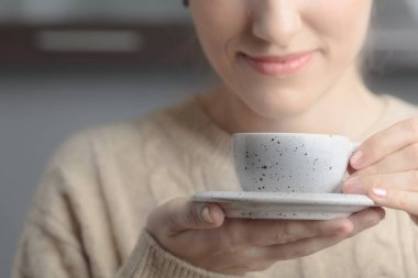  Çekici ve mutlu sarışın kazaklı kahve içiyor. Seçici odak.