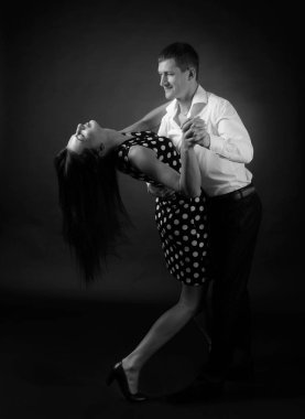 Puantiyeli elbise ve tango dans Beyaz tişörtlü adam genç güzel kadın. Stüdyoda dans aşk çift. Siyah ve beyaz.