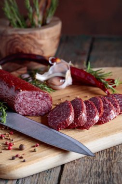 Eski ahşap bir masada tütsülenmiş salam. Biberiye, sarımsak ve biberli sosis..