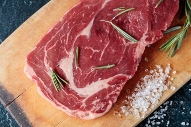 Taze çiğ Dana biftek biberiye ve deniz ile ahşap tahta üzerinde tuz. Üstten görünüm.