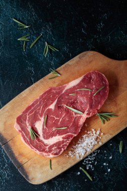 Taze çiğ Dana biftek biberiye ve deniz ile ahşap tahta üzerinde tuz. Üstten görünüm.