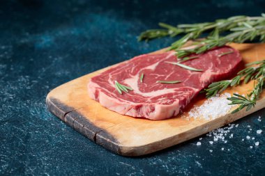 Taze çiğ Dana biftek biberiye ve deniz ile ahşap tahta üzerinde tuz.