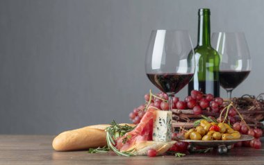 Prosciutto, mavi peynir ve koyu arkaplanda biberiyeli sandviç. Lezzetli aperatif ve kırmızı şarap. Metnin için boşluk kopyala.