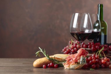 Prosciutto, mavi peynir ve koyu arkaplanda biberiyeli sandviç. Lezzetli aperatif ve kırmızı şarap. Metnin için boşluk kopyala.