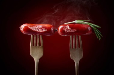 Rosemary bir çatal ile ızgara sosis. Koyu kırmızı arka plan, kopya alanı. 