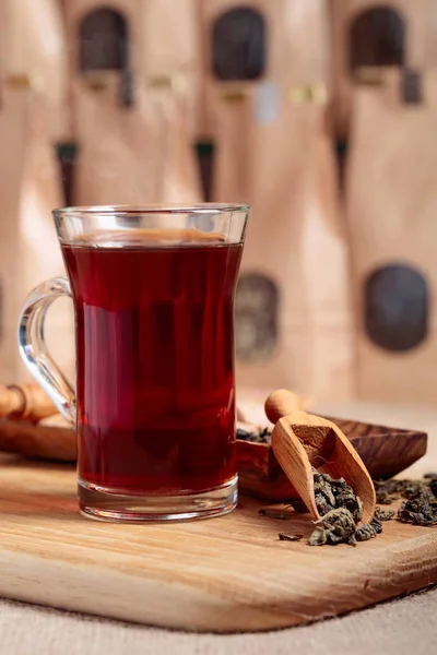 熱いお茶のグラス 乾燥茶葉と木製のスプーン ゆったりとしたお茶のための窓付きクラフト紙パック — ストック写真