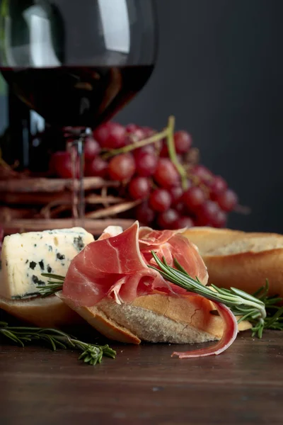 夹杂着意大利火腿 蓝奶酪和迷迭香的三明治 背景是深色的 美味的小吃和红酒复制您的文本空间 — 图库照片