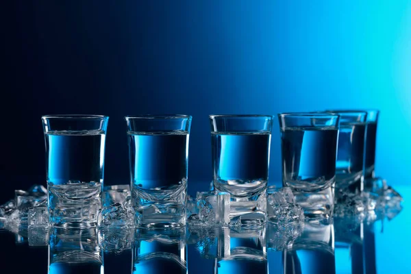 Vasos Vodka Con Hielo Una Mesa Vidrio Luz Azul — Foto de Stock