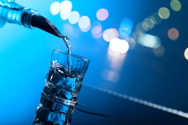 Vodka Viene Versata Dalla Bottiglia Bicchiere Sfondo Riflettente Luce Blu — Foto Stock