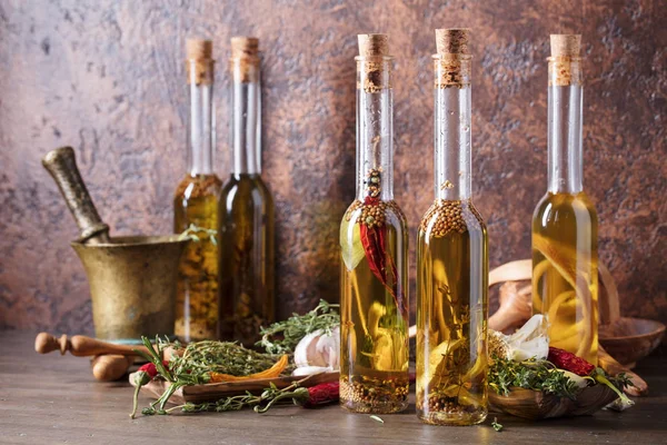一张旧木桌上的一瓶橄榄油 橄榄油用不同的香料和草本 — 图库照片