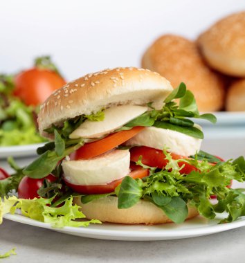 Mozzarella peyniri, domates ve yeşillik mutfak masasının üzerinde sandviç. Topuz susam, peynir ve salata ile.
