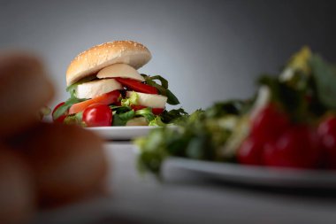 Mozzarella peyniri, domates ve yeşillik mutfak masasının üzerinde sandviç. Bun susam, peynir ve salata ile. Seçici odak.