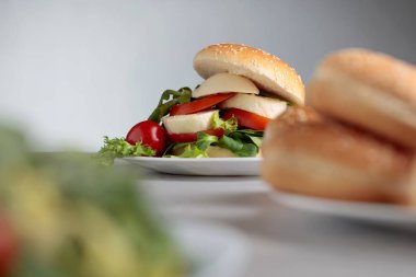 Mozzarella peyniri, domates ve yeşillik mutfak masasının üzerinde sandviç. Bun susam, peynir ve salata ile. Seçici odak. Kopya alanı.