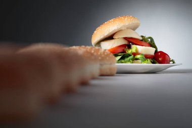 Mozzarella peyniri, domates ve yeşillik mutfak masasının üzerinde sandviç. Bun susam, peynir ve salata ile. Seçici odak.