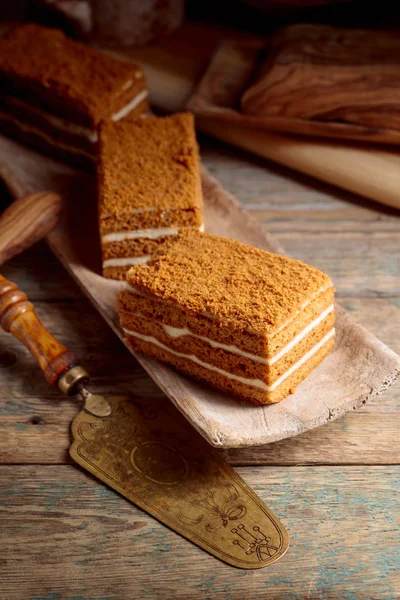 古い木製のテーブルの上のクリームと自家製の層状蜂蜜ケーキ — ストック写真