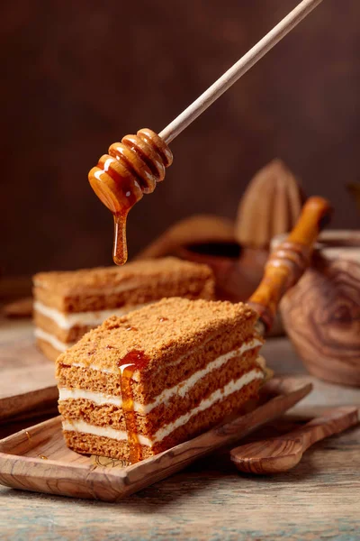 古い木製のテーブルの上のクリームと自家製の層状蜂蜜ケーキ — ストック写真
