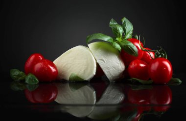Mozzarella fesleğen ve siyah bir tabloda domates ile.