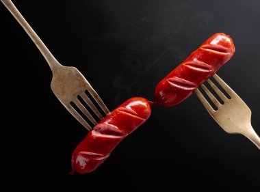Çatalda ızgara sosis. Siyah arkaplan, boşluğu kopyala. 