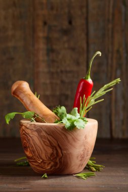 Eski ahşap bir masa üzerinde farklı otlar. Biberiye, kişniş, kekik ve maydanoz ile ahşap harç.