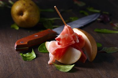 Eski ahşap bir masada armutlu jambon.