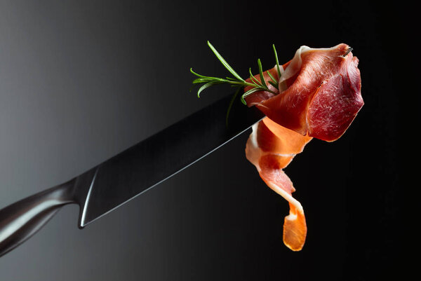Prosciutto with rosemary on a knife blade.  Copy space for your text.