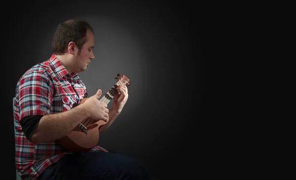 Αρσενικός Μουσικός Κάθεται Και Παίζει Γιουκαλίλι Οπίσθιος Φωτισμός Σκοτεινό Φόντο — Φωτογραφία Αρχείου