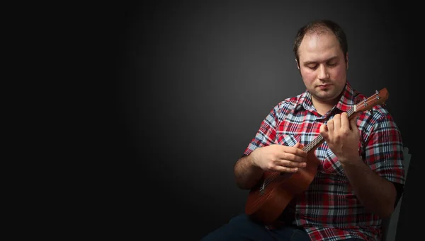 Αρσενικός Μουσικός Κάθεται Και Παίζει Γιουκαλίλι Σκοτεινό Φόντο Αντιγραφή Χώρου — Φωτογραφία Αρχείου
