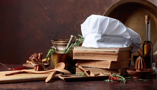 白いシェフの帽子と古い料理本 台所用品キッチン テーブルにローズマリーとスパイスが香る コピー スペース — ストック写真