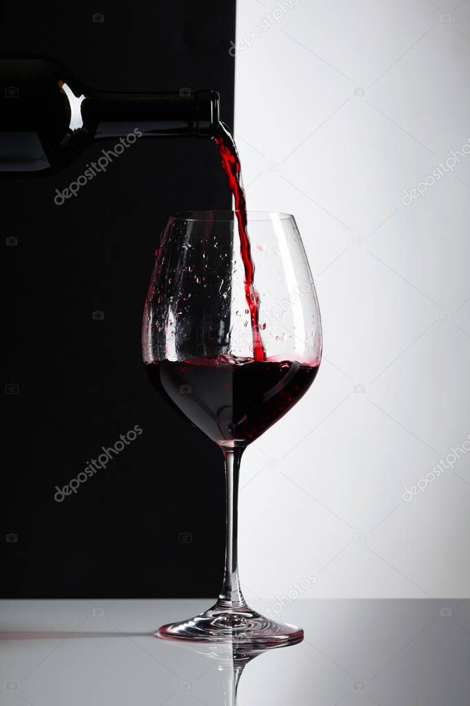 Red wine is poured into a glass. Reflexive background, copy space for your text.