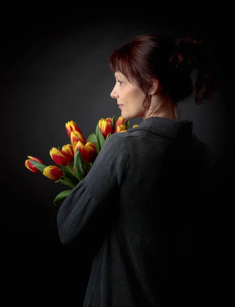 Attraktive Frau mit einem Strauß roter und gelber Tulpen. — Stockfoto